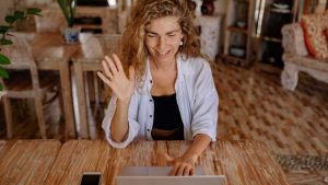 Happy woman with her hand raised in excitement, using laptop.