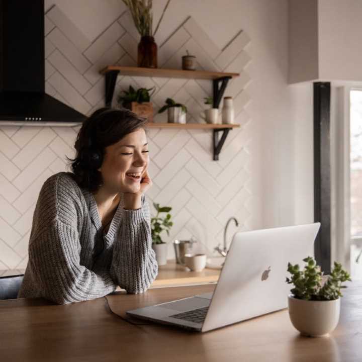 happy girl standing in kitchen using computer-katrin-bolovtsova