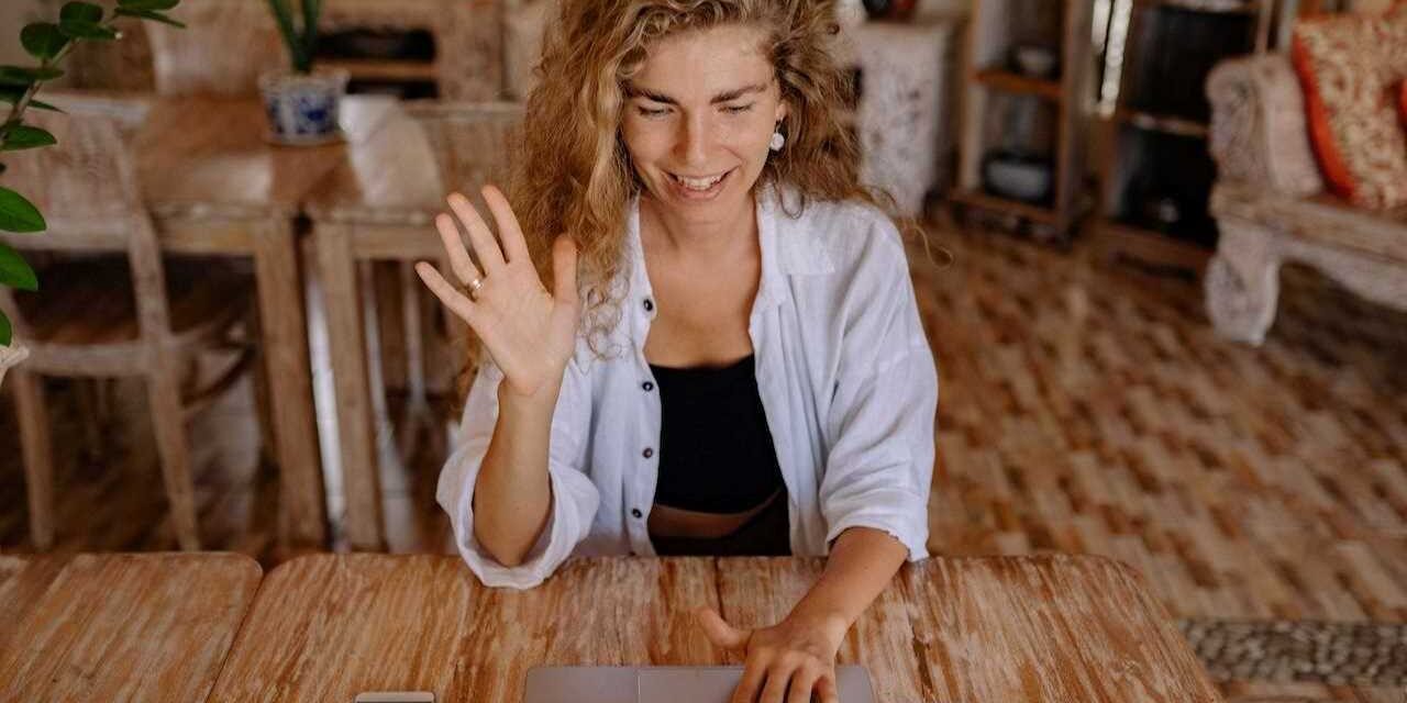 Happy woman with her hand raised in excitement, using laptop.
